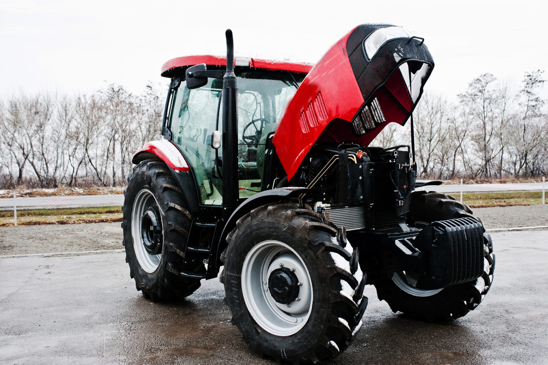 New red tractor with open motor at snowy weather equipment rentals